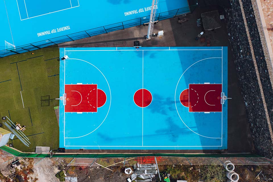 Top-down view of an outdoor basketball court with marked lines and hoops.