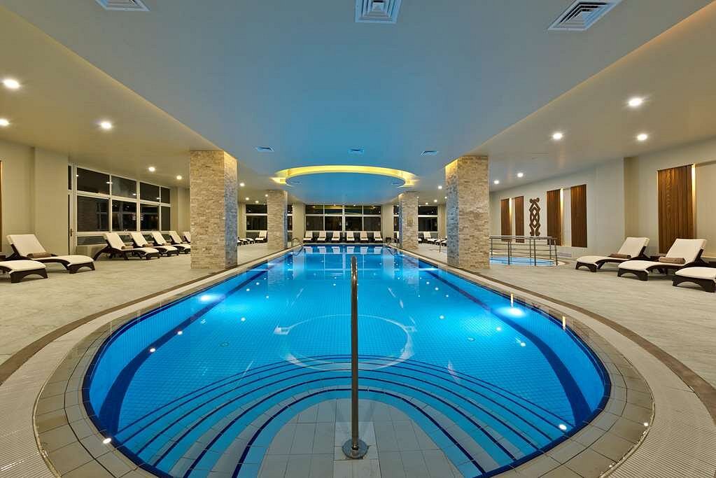 Indoor swimming pool with lounge chairs and modern lighting