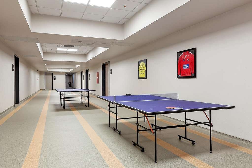 Hallway with two table tennis tables and framed jerseys on the walls