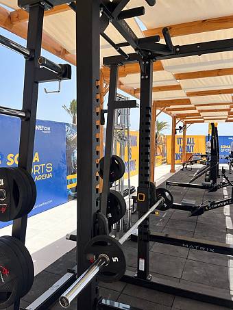Close-up of squat rack and weights in shaded outdoor gym facility