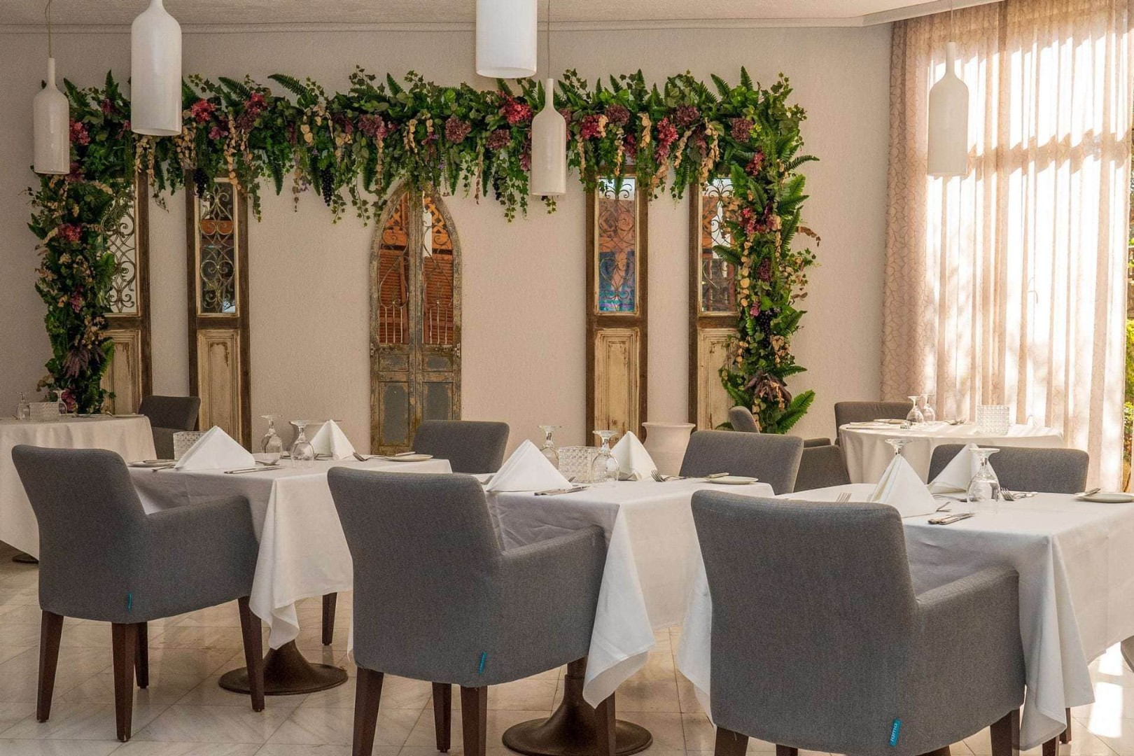 Elegant dining room with white tablecloths, gray chairs, and floral decor for team meals