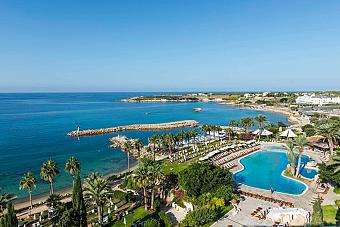 Aerial view of a beachfront resort with a large outdoor pool and sunbeds facing the sea