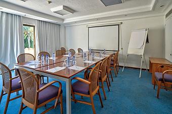 Meeting room with tables, chairs, whiteboard, and projector setup for coaching or team briefings