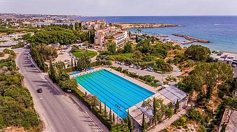 Seaside sports facility featuring a large outdoor swimming pool and nearby roads