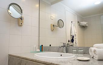Modern bathroom with white tiles, sink, mirror, and bathrobe on the wall