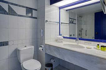 White-tiled bathroom with mirror, sink, and modern fixtures prepared for guests