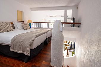 Loft-style hotel room with twin beds on an upper level and staircase below