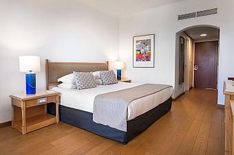 Cozy bedroom with king-size bed, bedside lamps, and minimalist decor for athlete accommodation