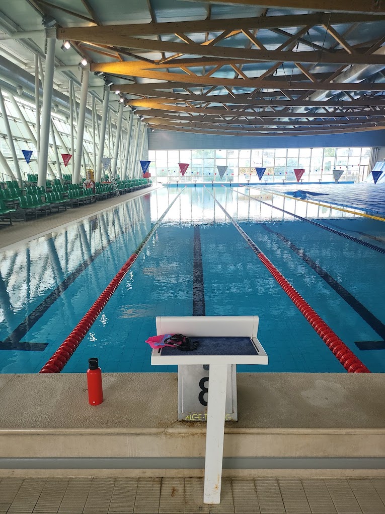 Indoor lap pool with starting block, lane ropes and seating along the deck.