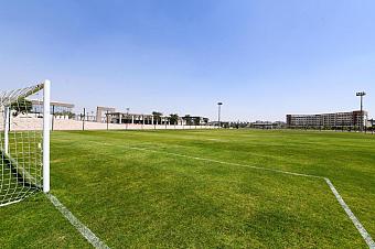 Green football field with white goalposts and boundary lines, used for team training sessions and practice drills