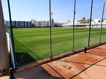 Green football field enclosed by a fence, suitable for athlete training sessions and practice drills