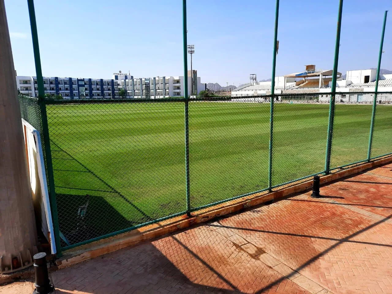 Green football field enclosed by a fence, suitable for athlete training sessions and practice drills