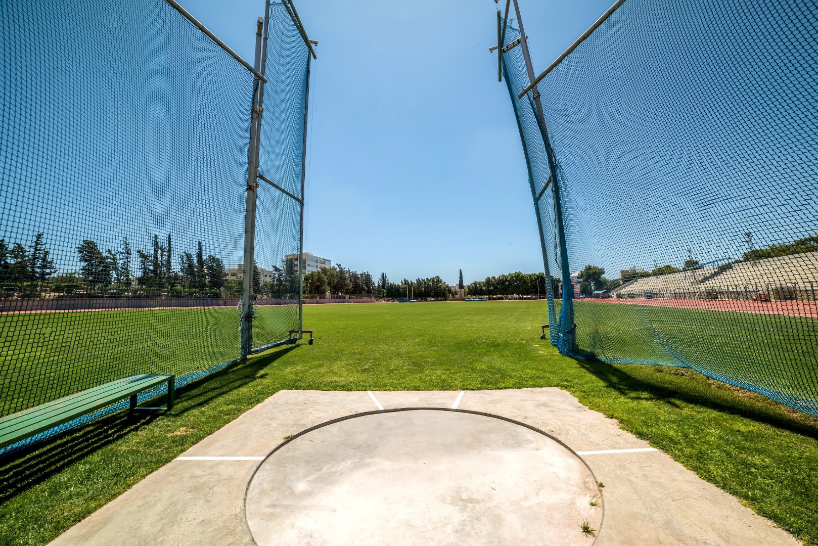 Hammer throw training area with safety nets and grass field under clear blue sky