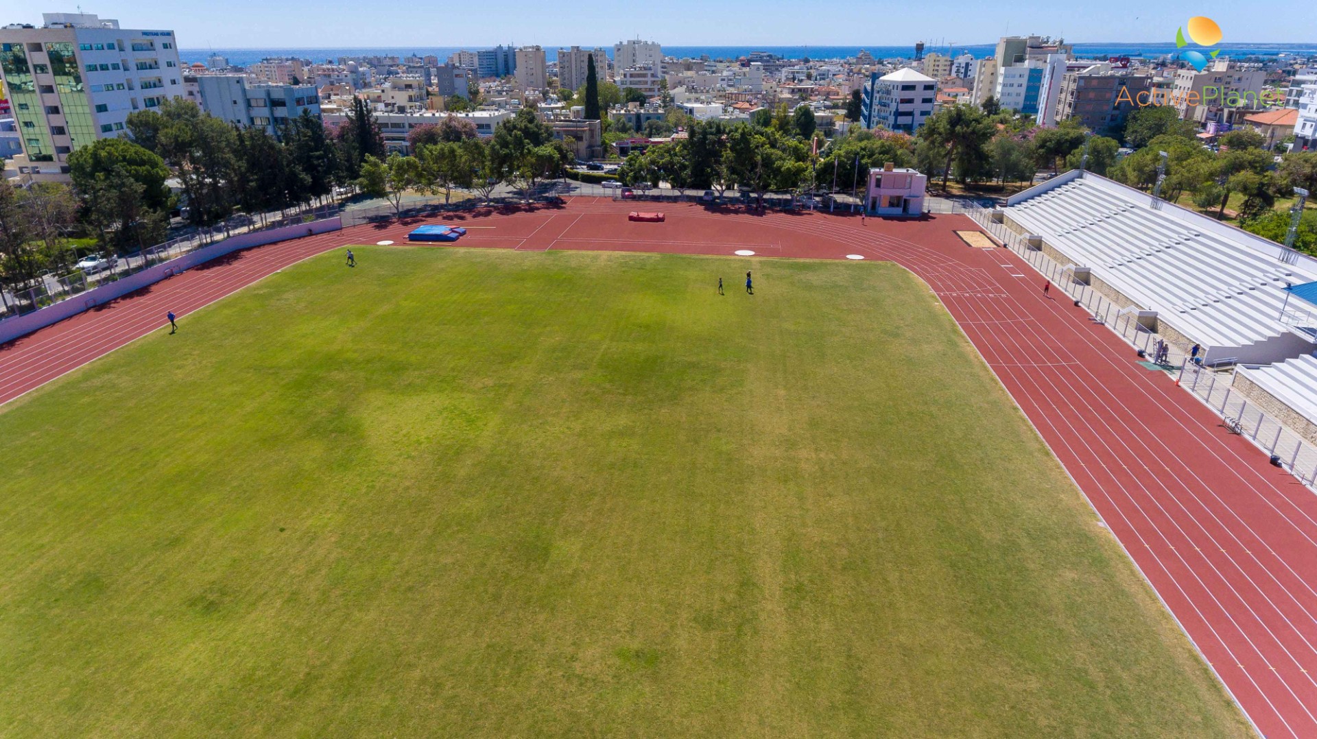 Aerial view of track and field stadium with green turf and red lanes for athletics training
