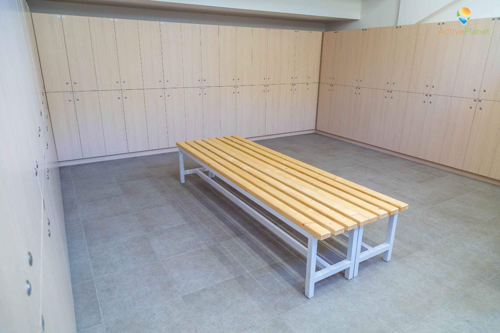 Locker room with wooden benches and storage lockers for training camp athletes