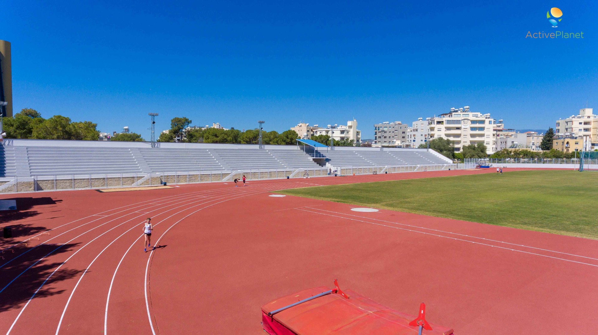Athletics track with red lanes and empty bleachers prepared for practice sessions