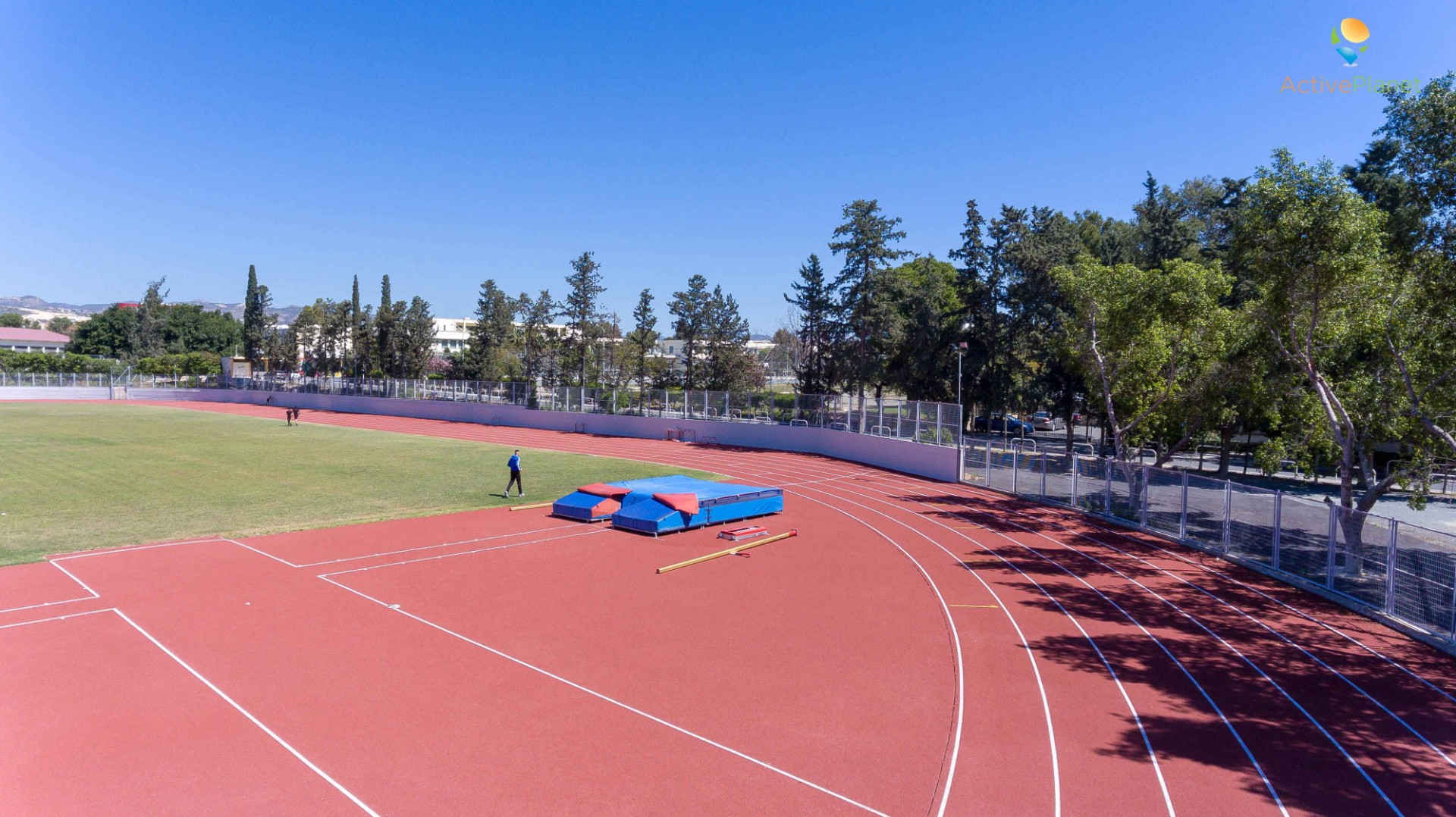 Corner of athletics field with pole vault mats and athletes during practice