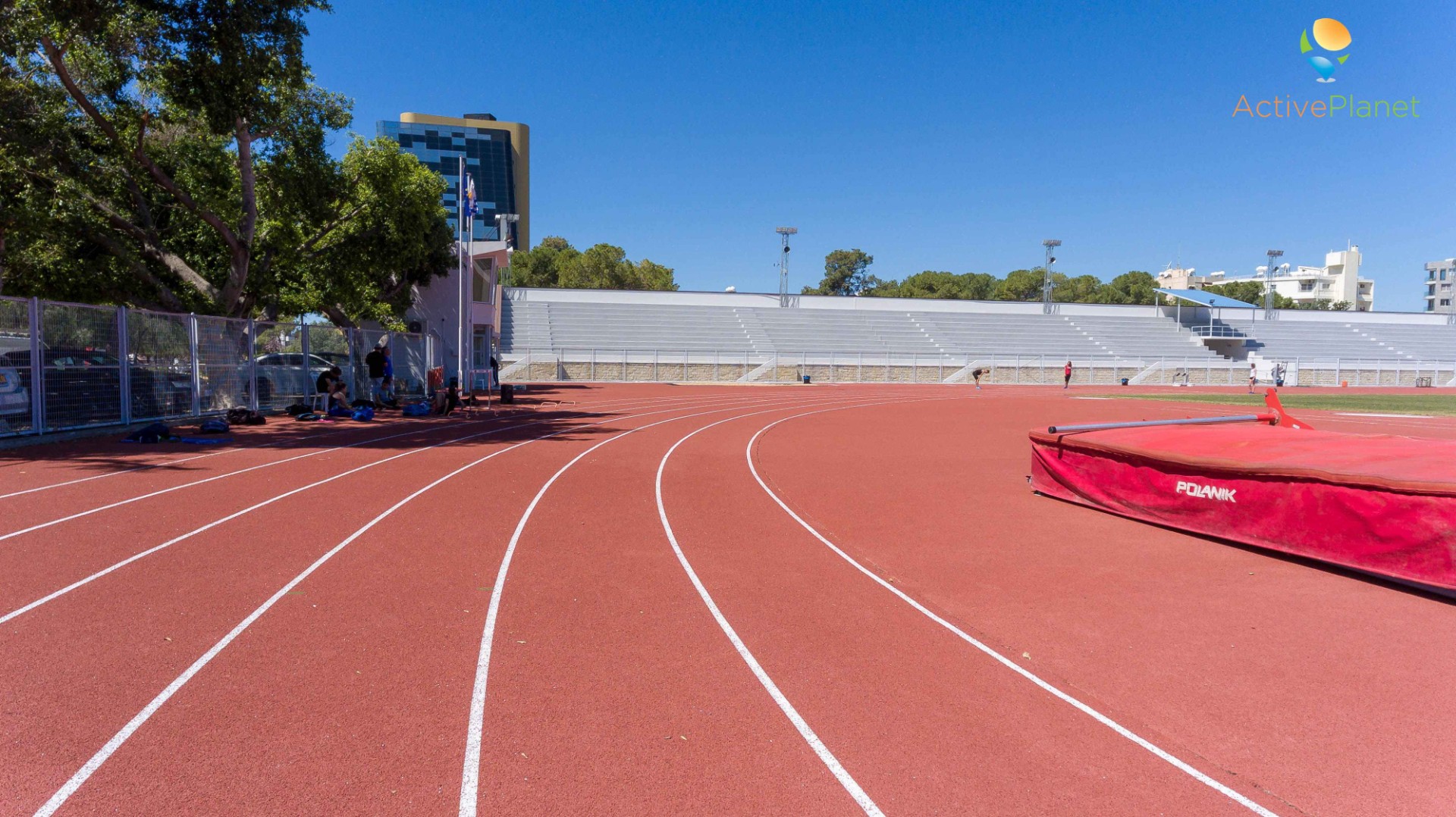 Running track curve with training equipment and shaded spectator stands