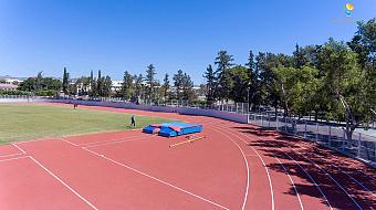 Corner of athletics field with pole vault mats and athletes during practice