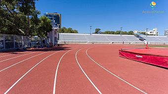 Running track curve with training equipment and shaded spectator stands