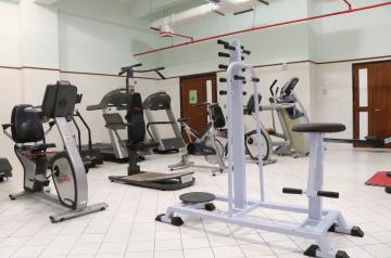 Kleiner Fitnessraum mit Cardiogeräten und Kraftgeräten auf gefliestem Boden.
