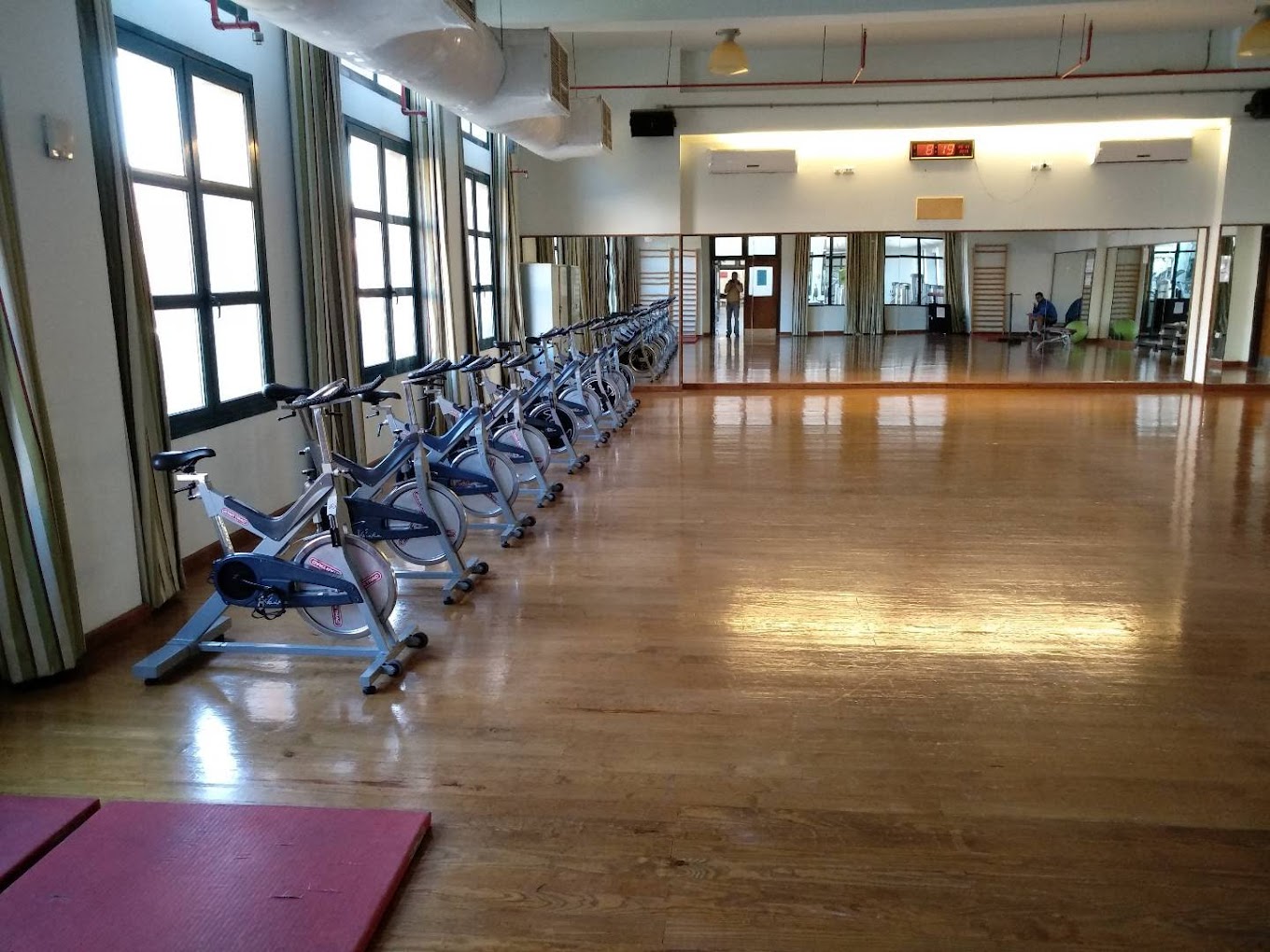 Fitnessstudio mit einer Reihe von Spinningrädern, Holzfußboden und Spiegelwand.