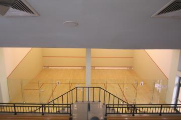 Squash-Courts in der Halle mit Holzfußboden und Glasrückwand, Blick von oben.