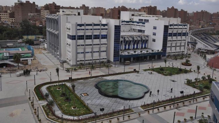 Exterior view of a large sports complex building with a paved plaza in front.