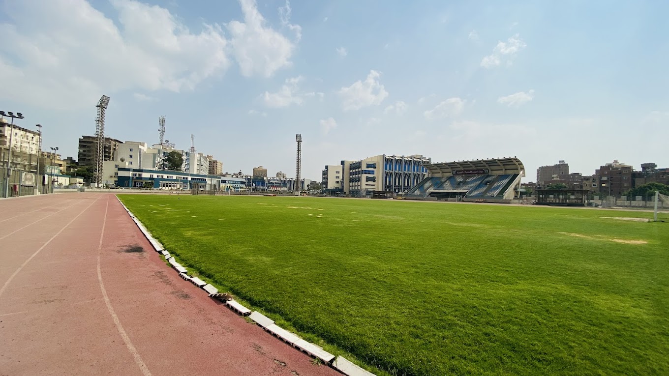 Outdoor stadium with athletics track, grass field, and covered grandstand.