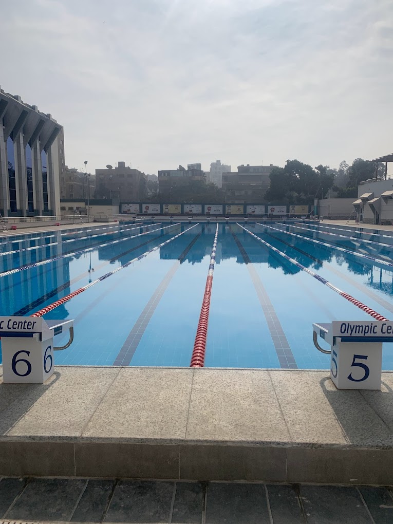Outdoor 50 m lane pool with starting blocks and lane ropes, prepared for swimming training camp sessions.