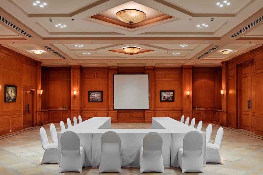 Wood-paneled meeting room with U-shaped tables and projector screen for training camp team briefing