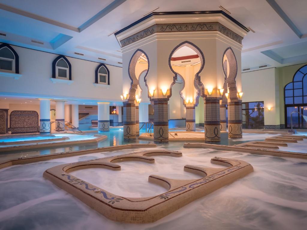 Indoor jacuzzi/thalasso area with foamy water and dramatic arches, relaxing recovery environment