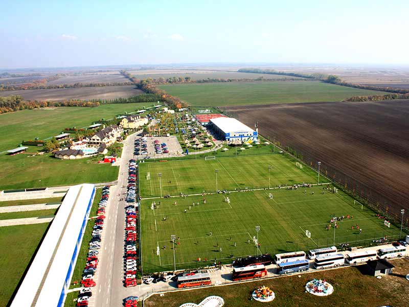 Aerial view of the resort complex showing sports fields, buildings, parking and surrounding countryside.