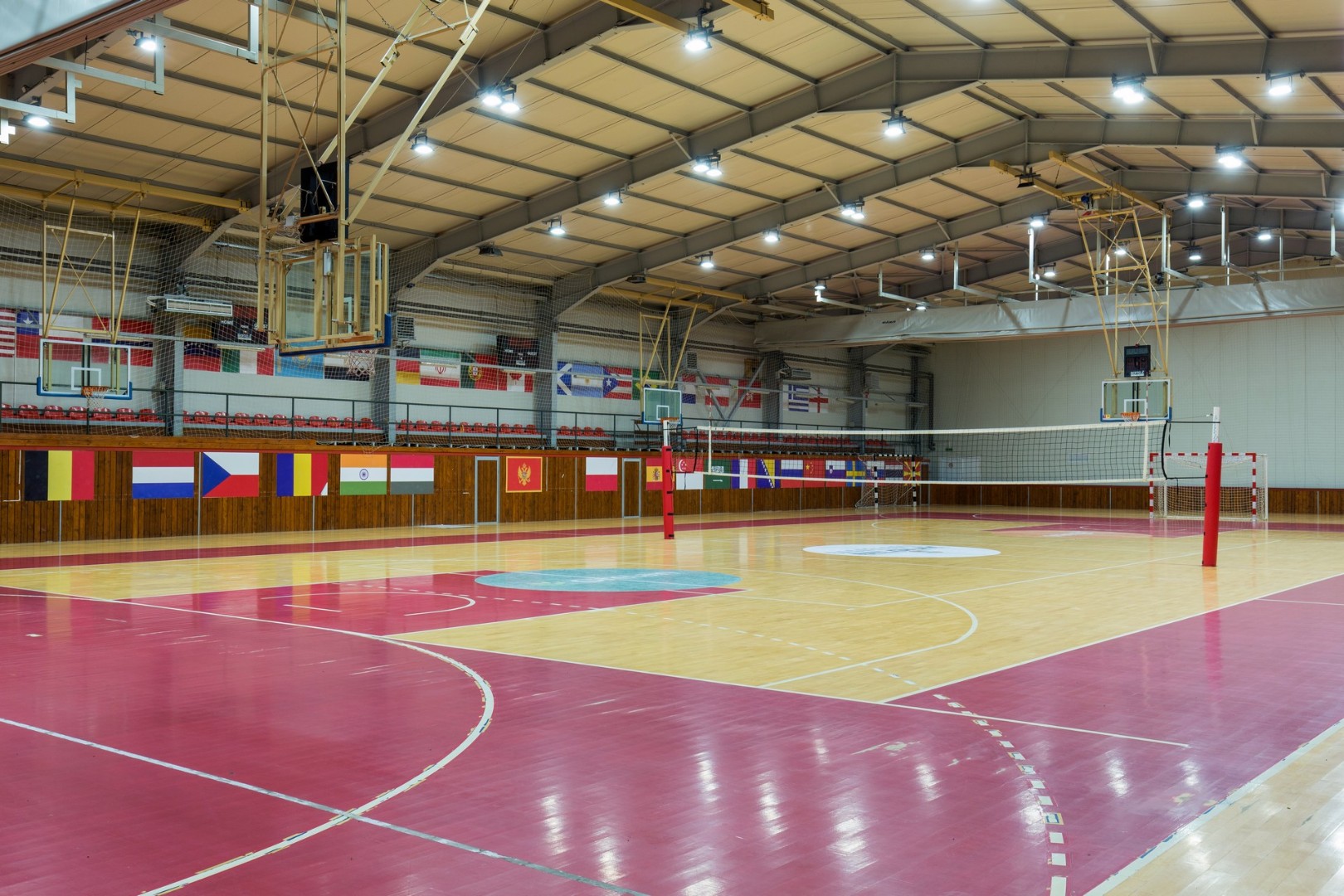 Large indoor sports hall with volleyball net and basketball hoops.