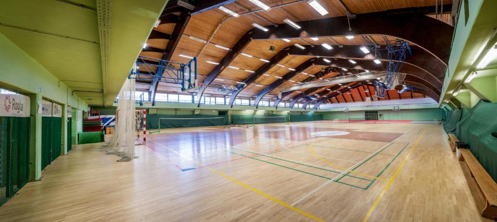 Indoor multi-sport hall with wooden floor, court markings, and basketball hoops.