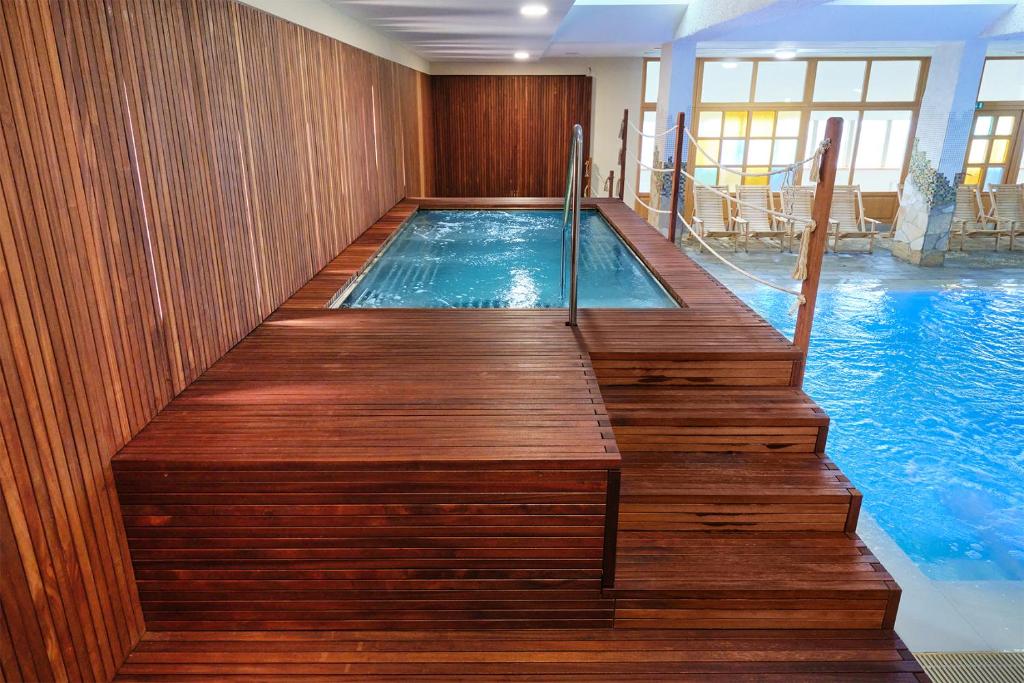Indoor pool area with raised whirlpool section and lounge chairs by large windows.