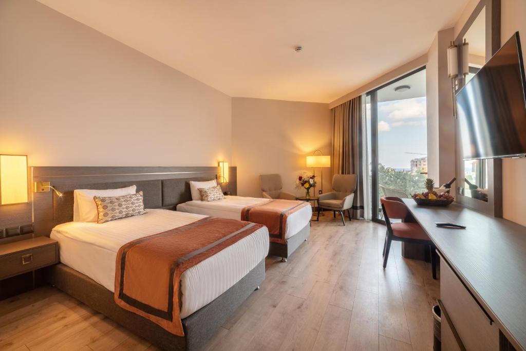 Twin room with two single beds, bedside lighting, desk, and balcony access with a sea view.