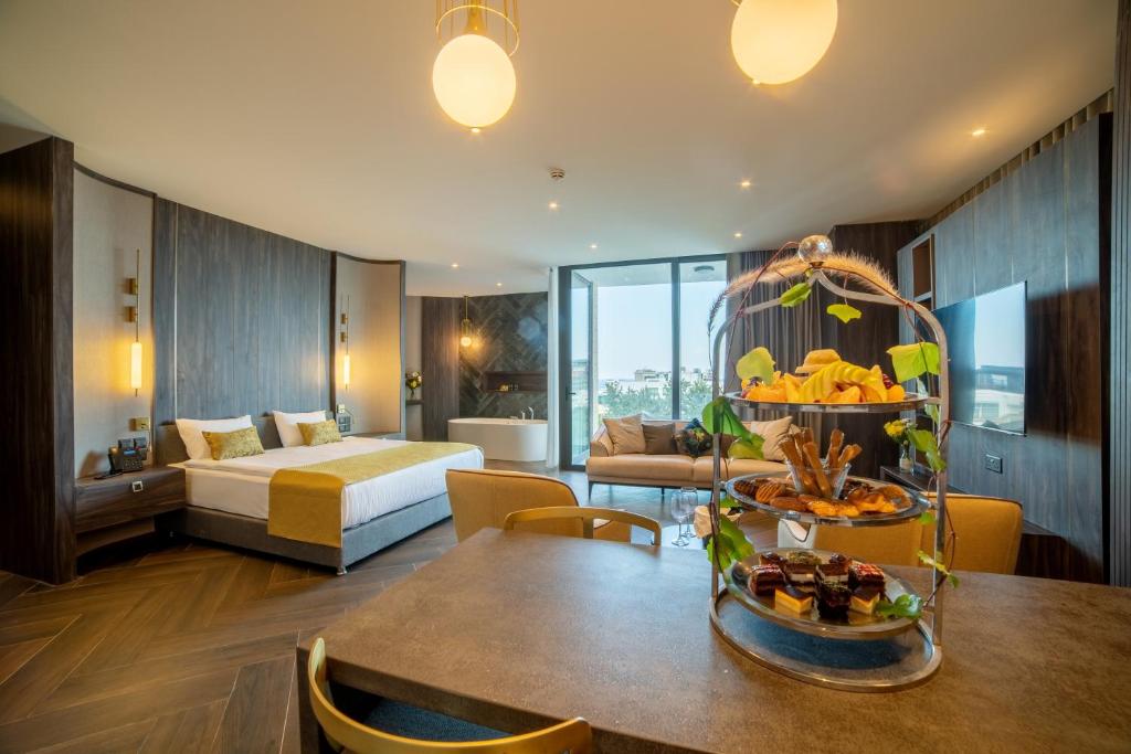 Large suite with double bed, dining table, seating area, and an in-room bathtub near the window.