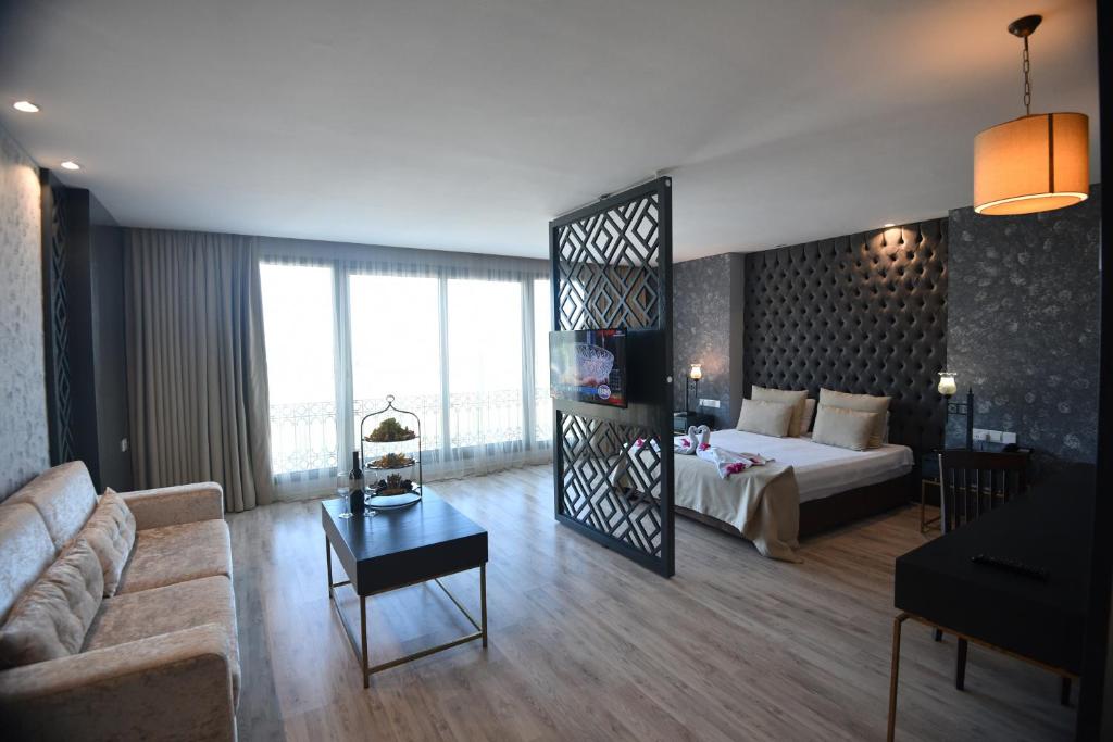 Spacious suite with double bed, sofa, coffee table, and decorative room divider by balcony windows.
