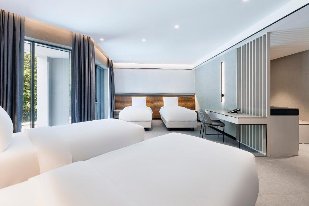 Großes, modernes Gästezimmer mit mehreren Betten, bodentiefen Fenstern und Arbeitsbereich.