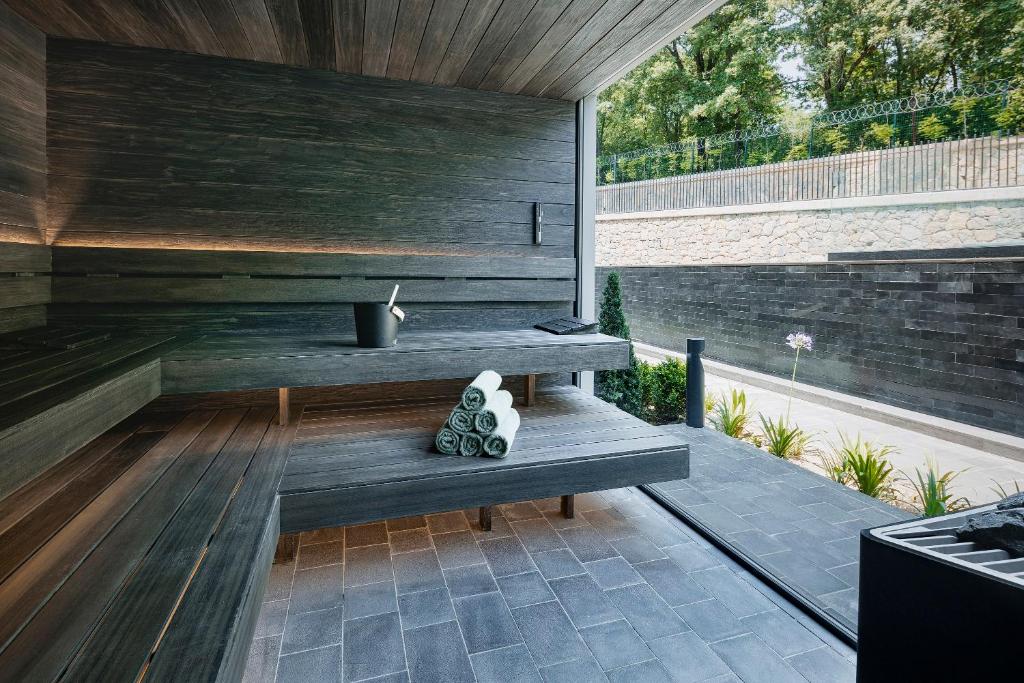 Moderne Sauna mit dunklen Holzliegen und Handtüchern am großen Fenster.