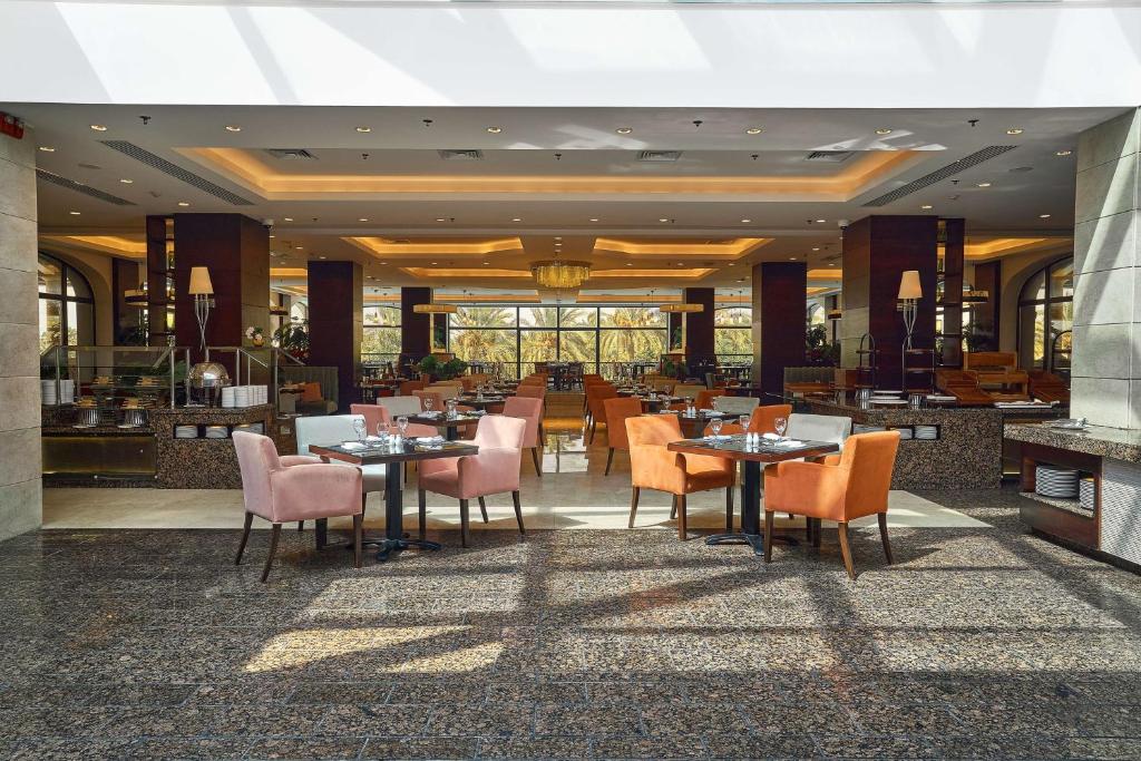 Restaurant dining area with set tables, upholstered chairs, and large windows.