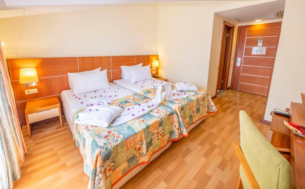 Twin room with two single beds, bedside lamps, desk, and wood flooring.