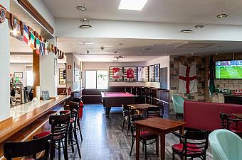 Sports bar lounge with pool table, seating and TV screens.