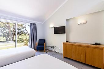 Twin guest room with TV, cabinet and large window overlooking the grounds.