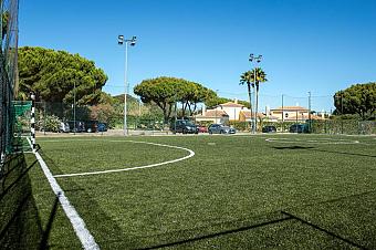 Fenced 5-a-side artificial turf football pitch with floodlights.