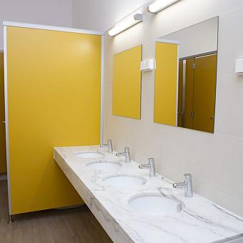 Modern shared bathroom with four sinks, mirrors, and yellow partitions.