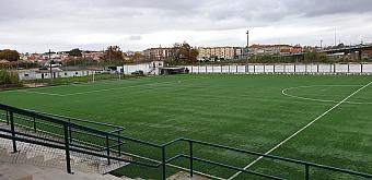 Empty artificial turf football pitch viewed from the stands on an overcast day.