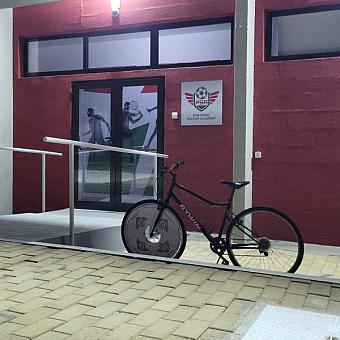 Entrance to the Portugal Soccer Academy building with a bicycle parked outside.