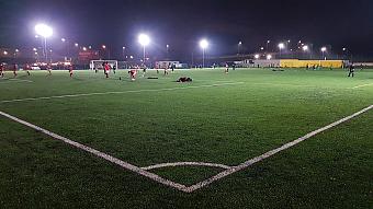 Floodlit artificial turf football pitch during an evening training session.